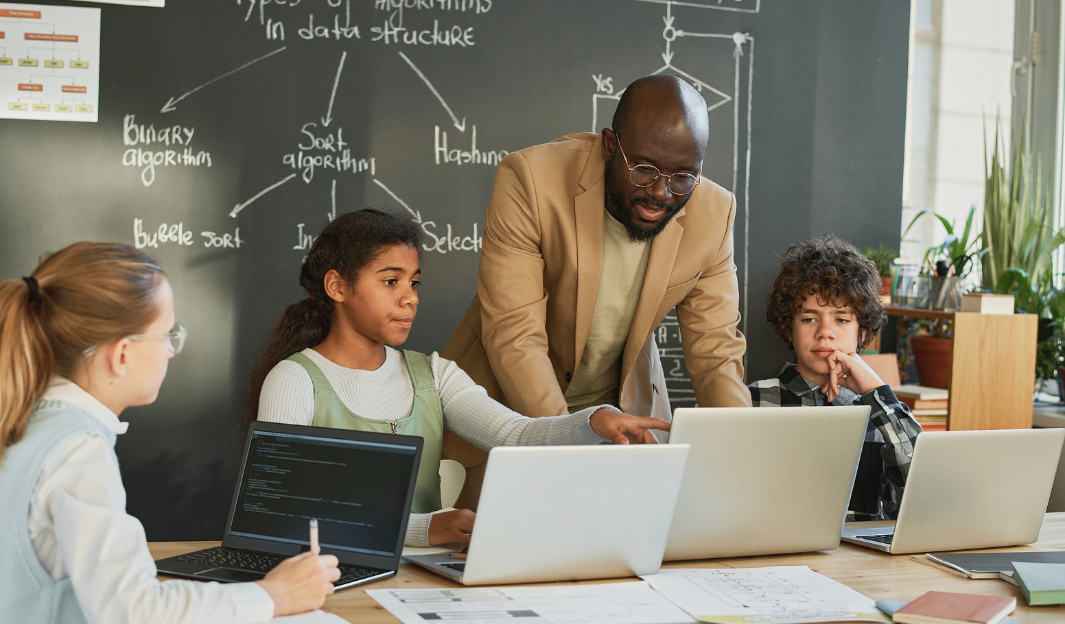 Teacher and students working on laptops in a classroom