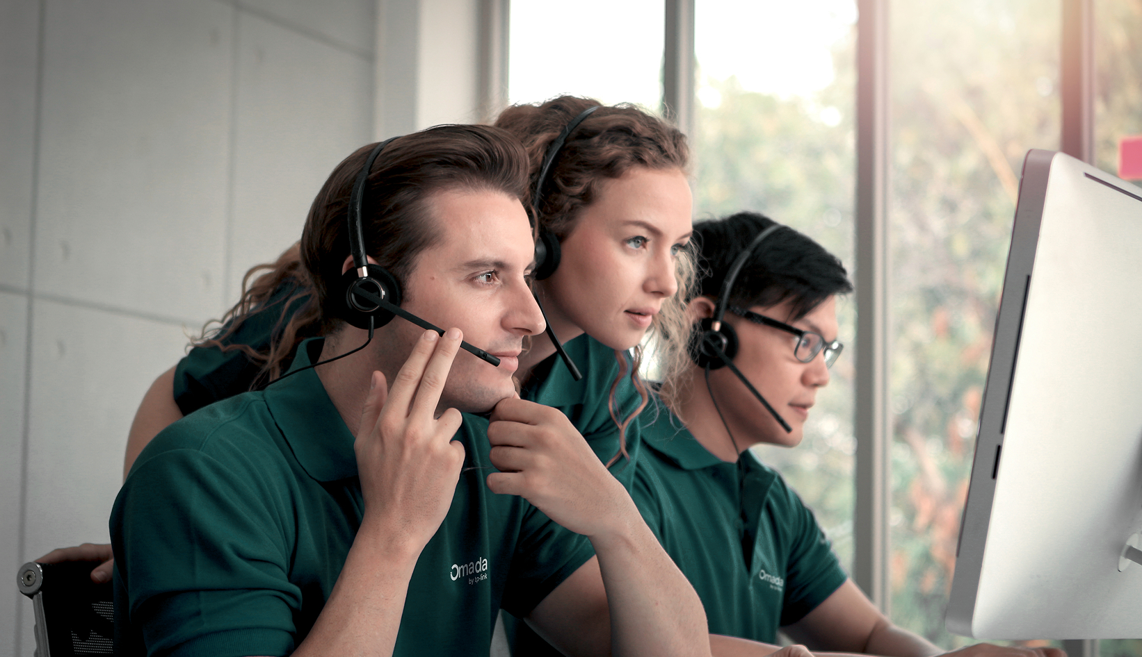 Three support personnel looking at a computer monitor